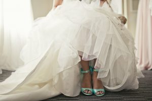 Bride’s tiffany blue shoes under her wedding dress.