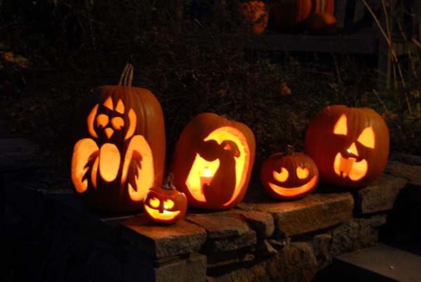carved pumpkins lit up at night for halloween party decorations