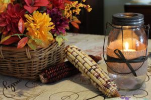 fall décor including corn, flowers and a candle with burlap