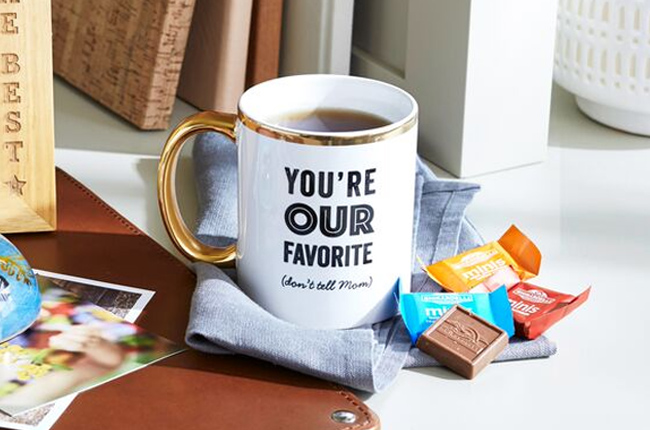 White, black, and gold cermaic mug that says "You're Our Favorite (don't tell Mom)"
