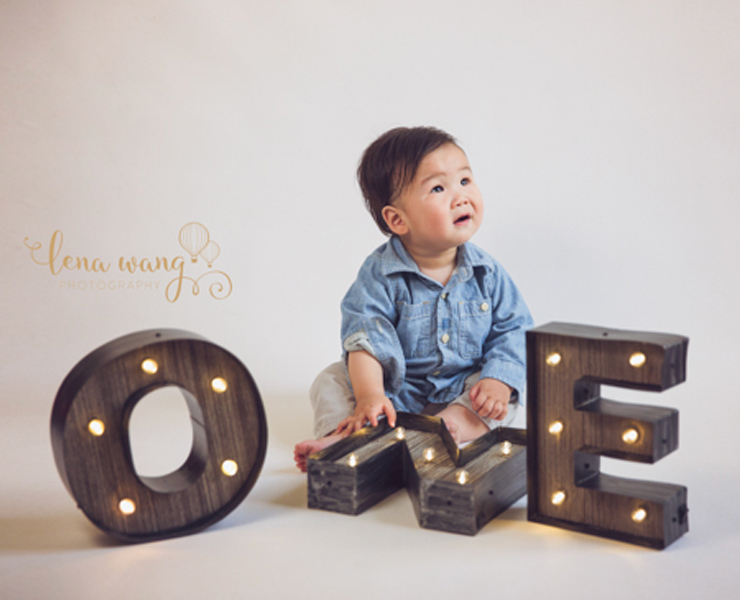 baby with wooden letters that spell one