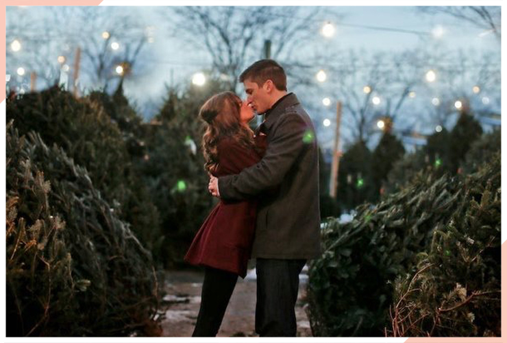 couple kiss whilst buying christmas tree christmas engagement photo