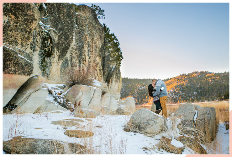 couples kiss by rockface and lake christmas engagement photo