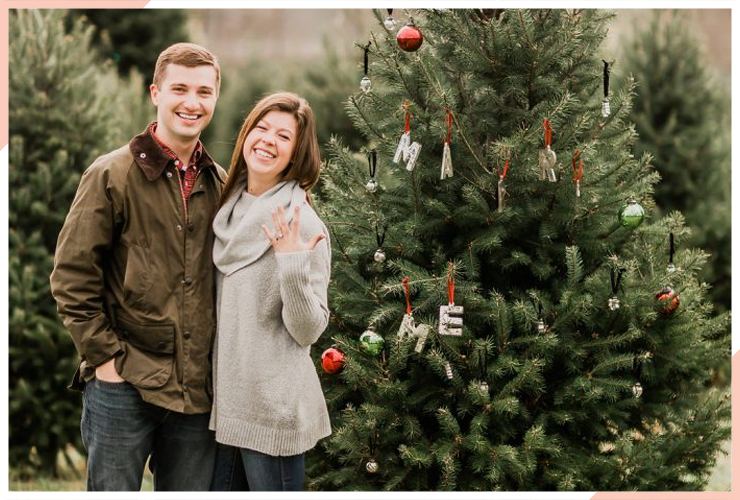 showing off ring by tree christmas engagement photo