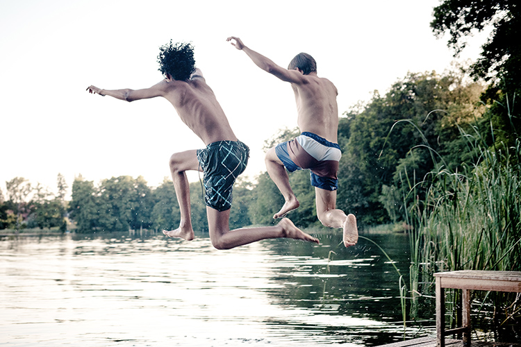 Friends jumping into lake