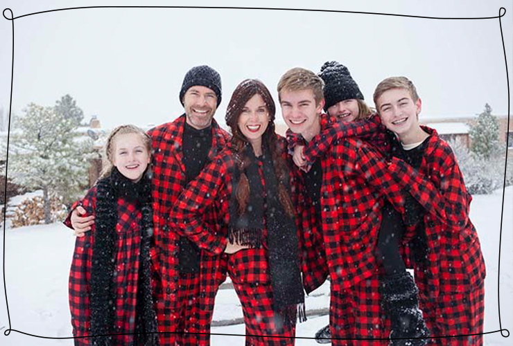 Family wearing Christmas onsies in falling snow