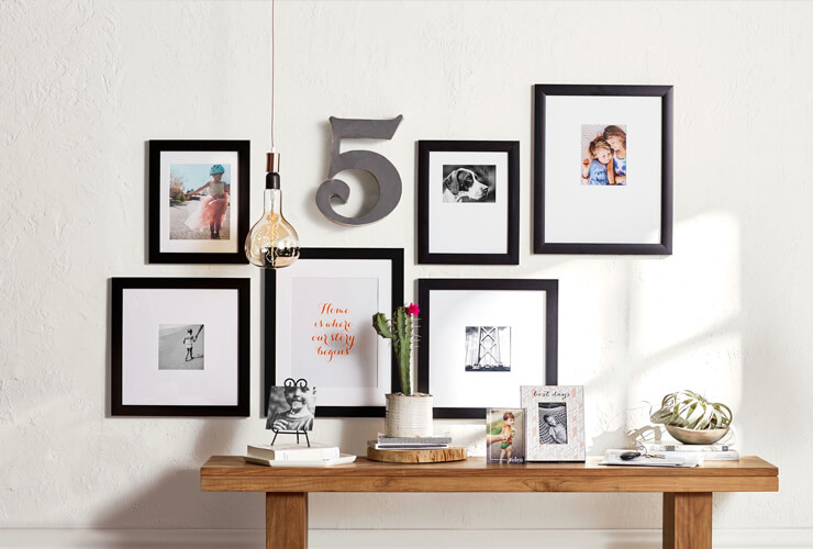 Photos are in black frames arranged on a wall