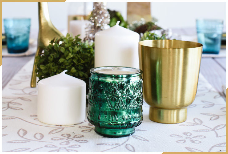 green gold and white candles with blue glasses in back