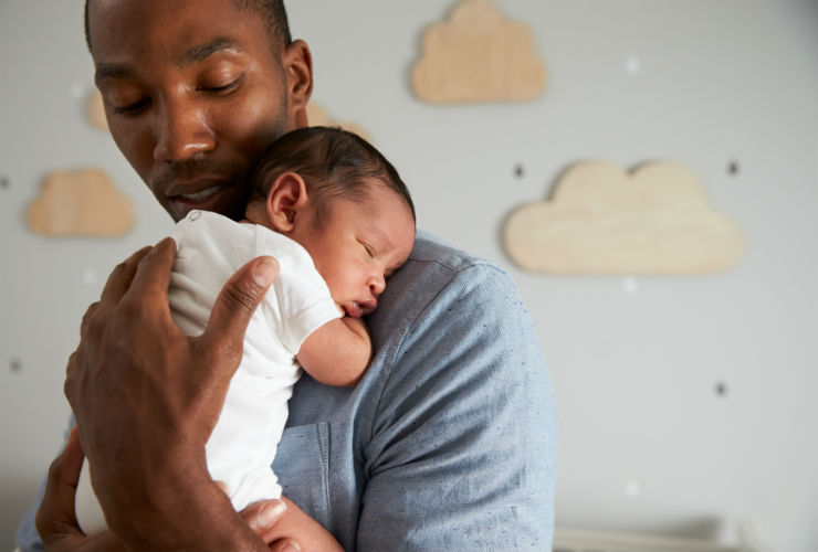 father holds baby over shoulder