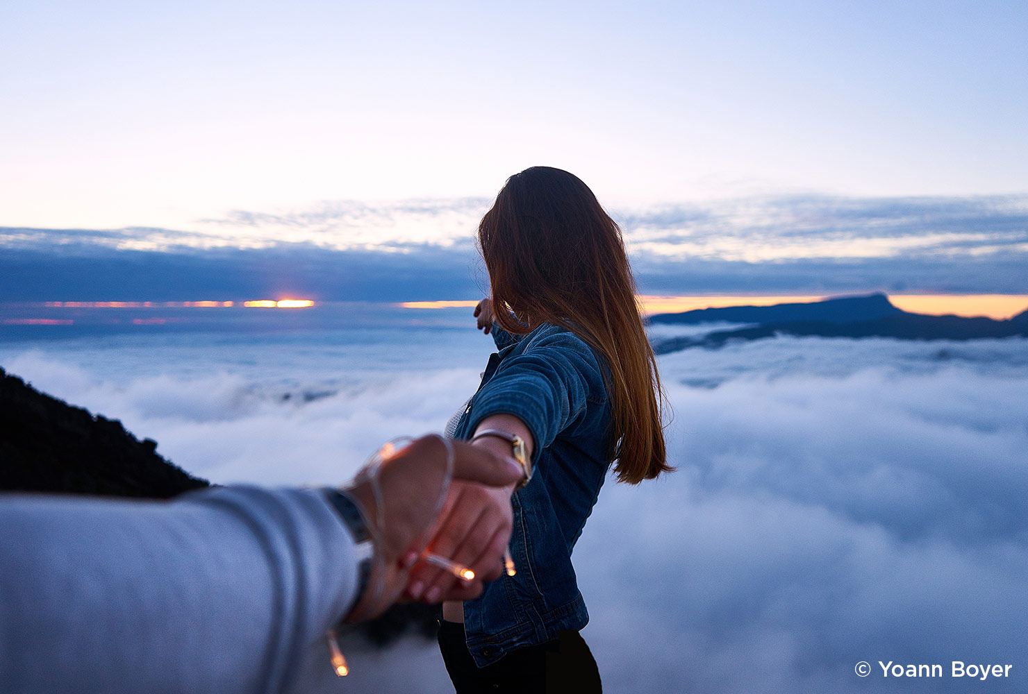 holding girl's hand above the clouds